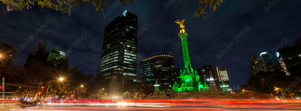 Panoramica de larga exposicion en el  Angel de la Independencia de la Ciudad de Mexico, de noche y con edificios de fondo. - obrazy, fototapety, plakaty 