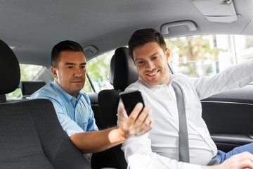 Wall Mural - transportation, vehicle and technology concept - middle aged male passenger on back seat showing his smartphone to car driver