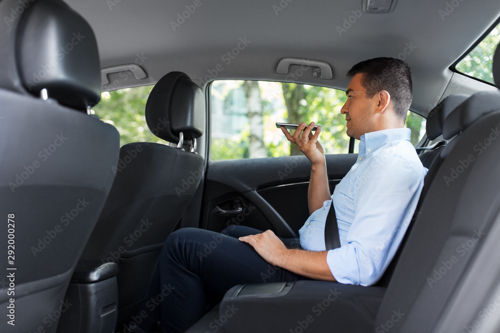 transport, business and technology concept - male passenger or businessman using voice command recorder on smartphone on back seat of taxi car