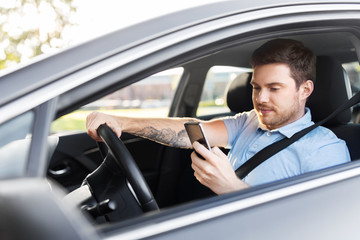 Wall Mural - transport, vehicle and technology concept - smiling man or driver driving car and using smartphone