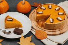  Pumpkin Pie On A Round Wooden Board, A Piece Of Cake On A White Plate Autumn Leaves And Small Pumpkins. Halloween Treats.