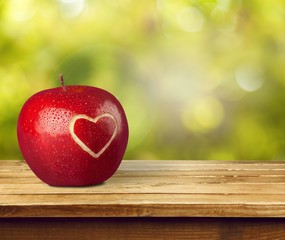 Poster - Fresh ripe apple with carved heart sign on wooden table