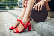 Stylish Shoes And Accessories. Young Woman Wearing Fashionable Red High-heeled Sandals And Holding Handbag