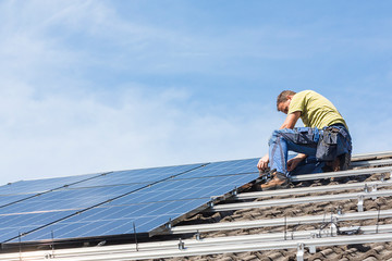 Wall Mural - Installing solar photovoltaic panel system. Solar panel technician installing solar panels on roof. Alternative energy ecological concept.