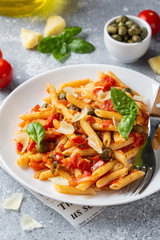 Wall Mural - Traditional pasta putanesca with tomato sauce (capers, onions, garlic, anchovies). Tasty Italian food with Parmesan cheese, vegetarian Penne