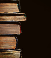 Wall Mural - A pile of an old yellowed with age books on the black background