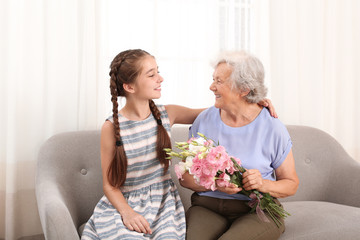 Wall Mural - Happy girl congratulating her grandmother at home