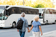 Senior couple of tourists on vacation in front of tourist bus