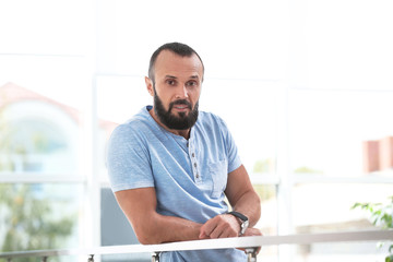 Wall Mural - Portrait of handsome mature man leaning on handrail indoors