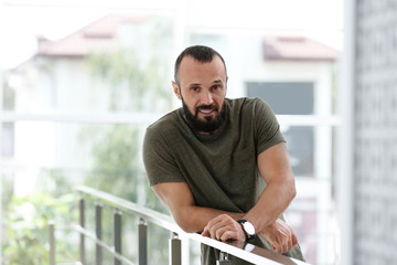 Wall Mural - Portrait of handsome mature man leaning on handrail indoors