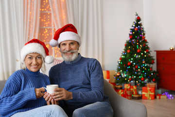 Wall Mural - Happy couple in Santa hats celebrating Christmas at home