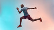 © Friends Stock - Full length of young african man in sports clothing jumping against colorful background