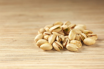 Wall Mural - Heap of pistachios on wooden background, close up with copy space