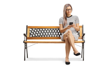 Poster - Young blond woman sitting on a bench and typing on a smartphone