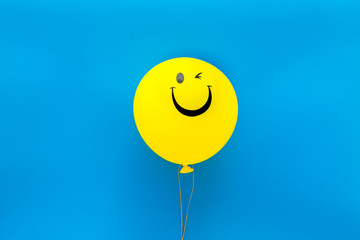 happiness emotion. yellow balloon with smile on blue background top view copy space