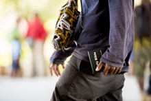 Close Shot Of A Male Holding A Bible Walking In The Street With A Blurred Background