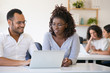© Mangostar - Happy diverse colleagues working on project together. Cheerful man and woman sitting at table in office, using laptop, looking at screen, smiling, talking. Teamwork concept