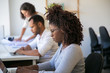 © Mangostar - African American software company employee working at workplace. Man and women in casual sitting at table and using laptops. Software company staff concept