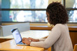 Focused African American female student working on computer in public place Young black woman sitting at desk and using laptop. Wireless technology concept