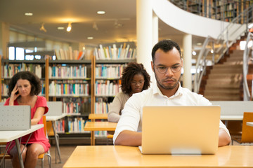 Wall Mural - focused adult students working in public library computer class. people sitting at desks and using l