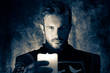 Atmospheric portrait of handsome knight with beard, looking at and holding candle up to camera while casting shadows