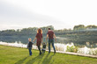 © satura_ - Parenthood and nature concept -Family of mother and father with two boys twins kids in a park at summer by a river at sunny day