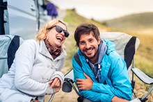 Young Couple Smiling With  Motorhome, RV Or Campervan On Beach.