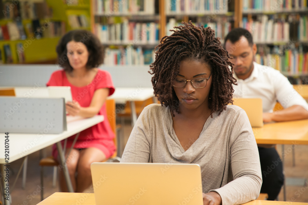 Serious African American student studying in library computer class ...