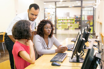 Wall Mural - instructor and trainees discussing corporate software in computer class. man and women sitting and s