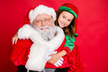 Close Up Photo Of Charming Christmas Father In Eyeglasses Eyewear And His Elf In Green Hat Cap Hugging Piggyback Isolated Over Red Background