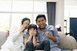 © FrameAngel - young family, father, mother and son watching TV feeling scared together in living room, happy family concept