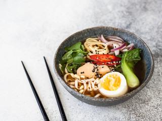 Wall Mural - Asian Ramen noodles with chicken, pak choi cabbage and egg on grey background. Copy space