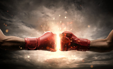 Boxing fight, close up of two fists hitting each other over dark, dramatic sky with copy space