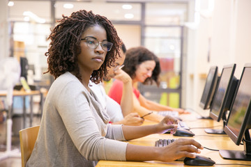 Wall Mural - african american adult student working in computer class. line of man and women in casual sitting at