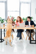 © LIGHTFIELD STUDIOS - three friends smiling and feeding golden retriever in office
