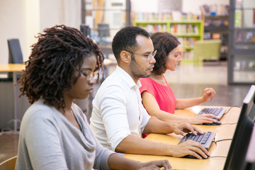 Wall Mural - multiethnic group of students studying in computer class. line of man and women in casual sitting at