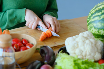 girl cuts a carrot with a knife to make a salad. 