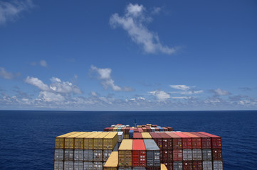 Large cargo container ship loaded with colorful containers sailing through a blue ocean.  