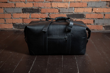 Men's accessories with black leather bags on wooden floor over wall background