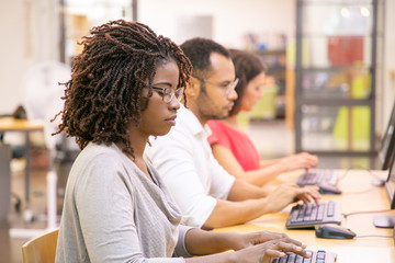 Wall Mural - diverse group of trainees studying in computer class. line of man and women in casual sitting at tab
