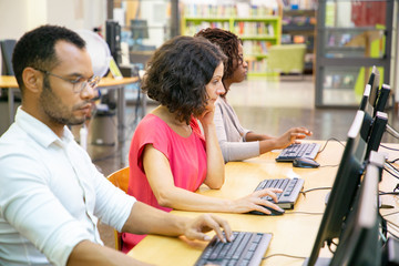 Wall Mural - diverse adult students working in computer class. line of man and women in casual sitting at table, 