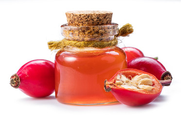 Rose-hips and rosehip seed oil on the white background.