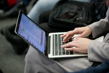 A picture of laptop. Girl holds it on her lap. She has her fingers on its keyboard. Woman types. She works