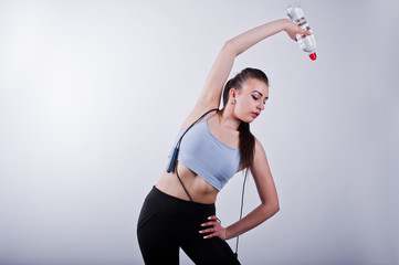 Cheerful attractive young fitness woman in top and black leggings with jump rope and bottle of water isolated over white background.