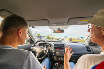 two mature men in a car driving through a city tunnel.