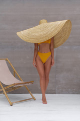 Beautiful young girl in a straw hat in a yellow bathing suit