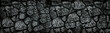 Natural granite stone wall wide texture. Dark rock masonry widescreen gloomy gothic background