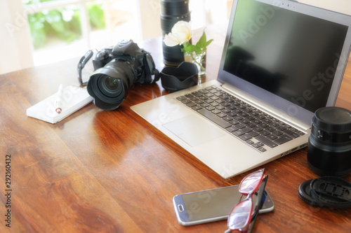 Fotomural workplace of a female photographer with laptop, camera and lenses on a wooden ta