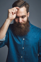 Wall Mural - Stylish young man with a beard styling his hair