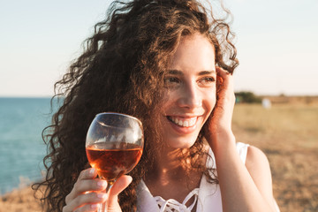 Poster - Photo of cheerful young woman holding wine glass and smiling